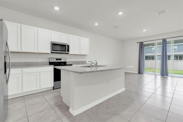 33036 Frosted Clover Way, Wesley Chapel, FL 33545 - kitchen featuring stainless steel appliances, light tile patterned flooring, white cabinets, a kitchen island with sink, and recessed lighting