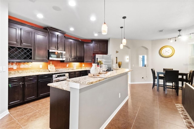 317 Royal Bonnet Dr, Apollo Beach, FL 33572 - kitchen featuring appliances with stainless steel finishes, arched walkways, light tile patterned floors, recessed lighting, and dark brown cabinetry