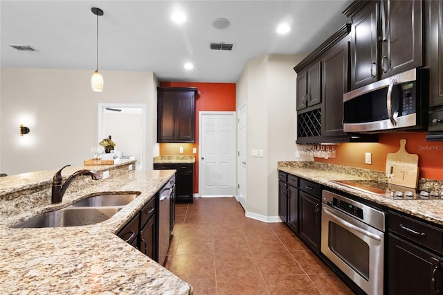 317 Royal Bonnet Dr, Apollo Beach, FL 33572 - kitchen with appliances with stainless steel finishes, dark tile patterned floors, light stone counters, hanging light fixtures, and recessed lighting