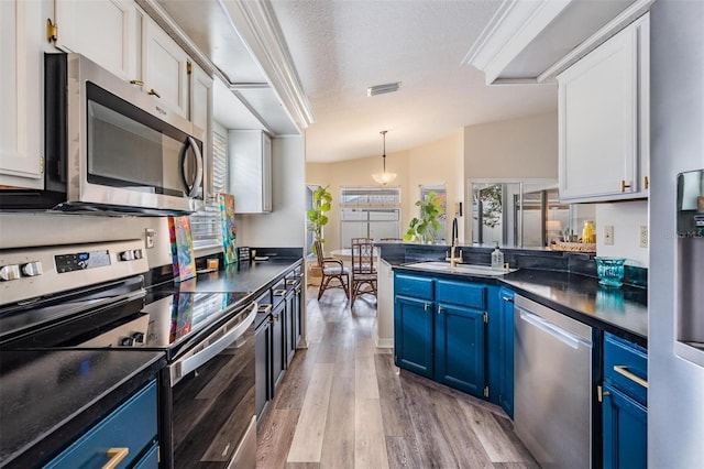 2208 Cattleman Dr, Brandon, FL 33511 - kitchen with appliances with stainless steel finishes, blue cabinetry, dark countertops, light wood-style floors, and a textured ceiling