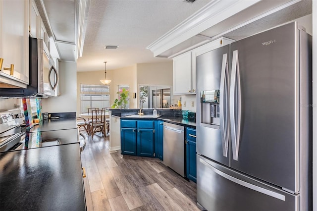 2208 Cattleman Dr, Brandon, FL 33511 - kitchen with appliances with stainless steel finishes, blue cabinets, a peninsula, dark countertops, and light wood-style flooring
