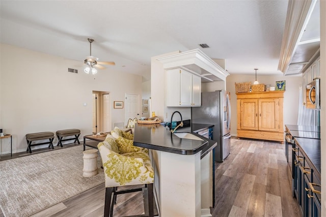 2208 Cattleman Dr, Brandon, FL 33511 - kitchen with dark countertops, white cabinets, a peninsula, appliances with stainless steel finishes, and light wood-style flooring