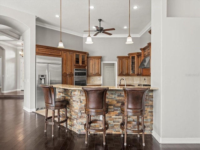 4521 Cheval Blvd, Lutz, FL 33558 - kitchen featuring appliances with stainless steel finishes, under cabinet range hood, arched walkways, ceiling fan, and brown cabinetry