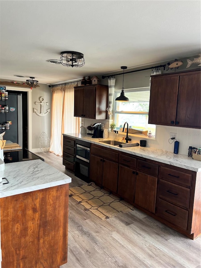 4119 Chambers St, Lake Wales, FL 33898 - kitchen with appliances with stainless steel finishes, light wood-style floors, dark brown cabinetry, hanging light fixtures, and light stone countertops