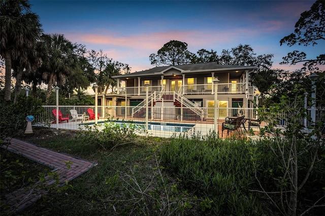 4915 S Rd, New Port Richey, FL 34652 - back of house at dusk with stairway, a patio area, and a balcony