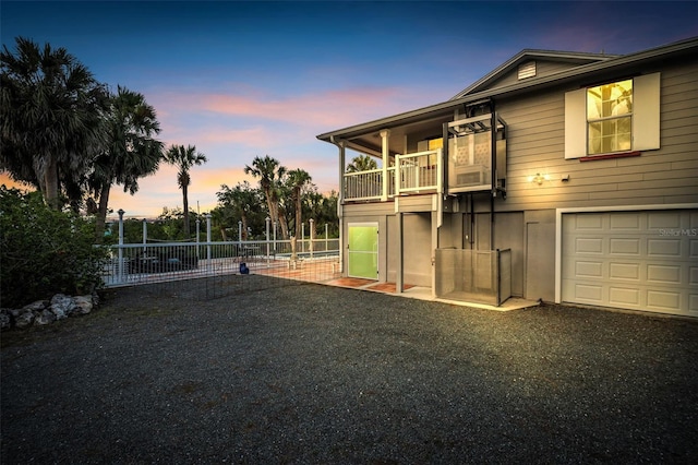 4915 S Rd, New Port Richey, FL 34652 - back of house at dusk with a garage, a balcony, and asphalt driveway