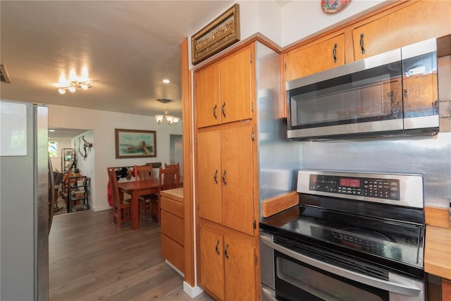 33 Cypress Dr, Palm Harbor, FL 34684 - kitchen with stainless steel appliances, wood finished floors, a chandelier, light countertops, and brown cabinets