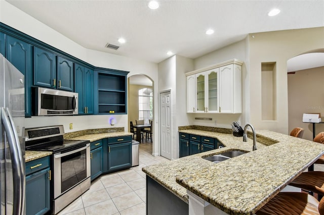 2009 Raven Manor Dr, Dover, FL 33527 - kitchen with stainless steel appliances, arched walkways, a breakfast bar area, blue cabinetry, and light stone counters