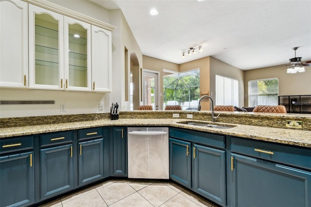 2009 Raven Manor Dr, Dover, FL 33527 - kitchen with stainless steel dishwasher, blue cabinetry, light tile patterned floors, white cabinetry, and light stone counters