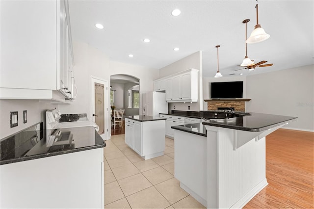 2702 Rogers Ranch Rd, Lithia, FL 33547 - kitchen with white refrigerator with ice dispenser, a ceiling fan, arched walkways, dark countertops, and a peninsula