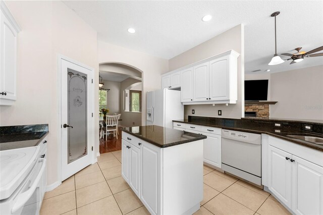 2702 Rogers Ranch Rd, Lithia, FL 33547 - kitchen with white appliances, arched walkways, white cabinets, dark countertops, and decorative light fixtures