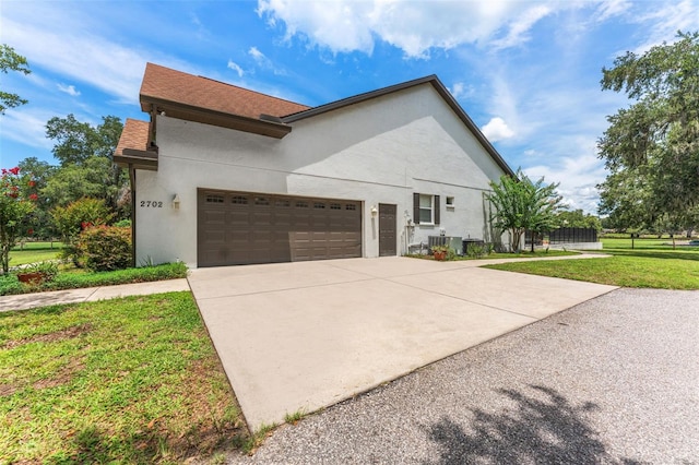 2702 Rogers Ranch Rd, Lithia, FL 33547 - view of property exterior with stucco siding, a garage, driveway, and a lawn