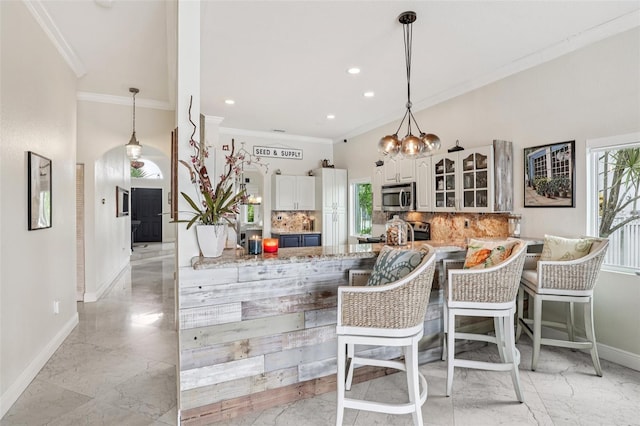 17001 NW 20th St, Pembroke Pines, FL 33028 - kitchen with stainless steel microwave, light marble finish flooring, ornamental molding, backsplash, and glass insert cabinets