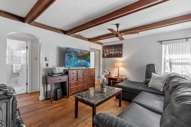 1222 Palm St, Clearwater, FL 33755 - living room featuring arched walkways, a textured wall, ceiling fan, wood finished floors, and beam ceiling