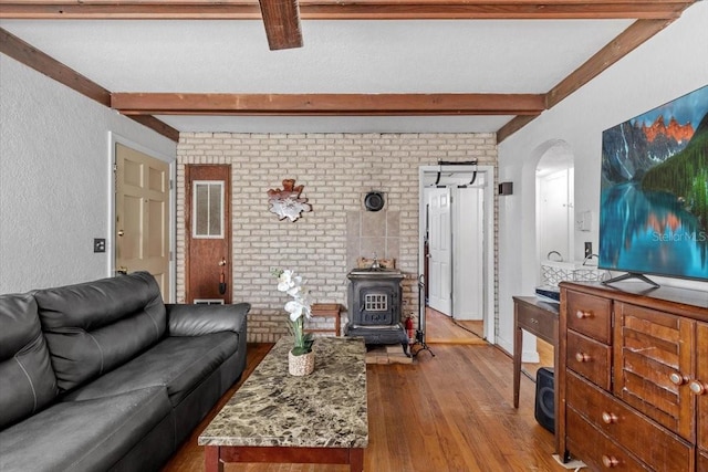 1222 Palm St, Clearwater, FL 33755 - living room featuring beamed ceiling, a wood stove, hardwood / wood-style flooring, arched walkways, and a textured wall