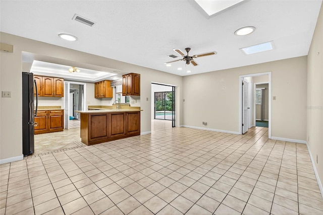 524 Garrard Dr, Temple Terrace, FL 33617 - kitchen with freestanding refrigerator, open floor plan, brown cabinets, light tile patterned flooring, and light countertops