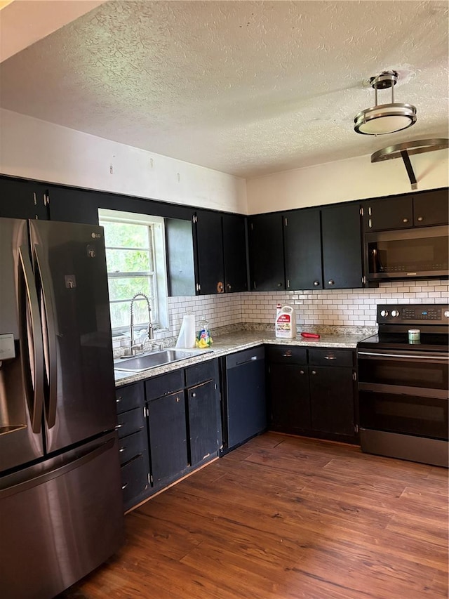 1214 Mitchell St, Brandon, FL 33511 - kitchen with stainless steel appliances, a textured ceiling, dark wood finished floors, dark cabinetry, and tasteful backsplash