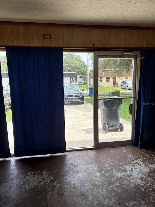 1214 Mitchell St, Brandon, FL 33511 - doorway to outside featuring concrete flooring, plenty of natural light, a textured ceiling, and wooden walls