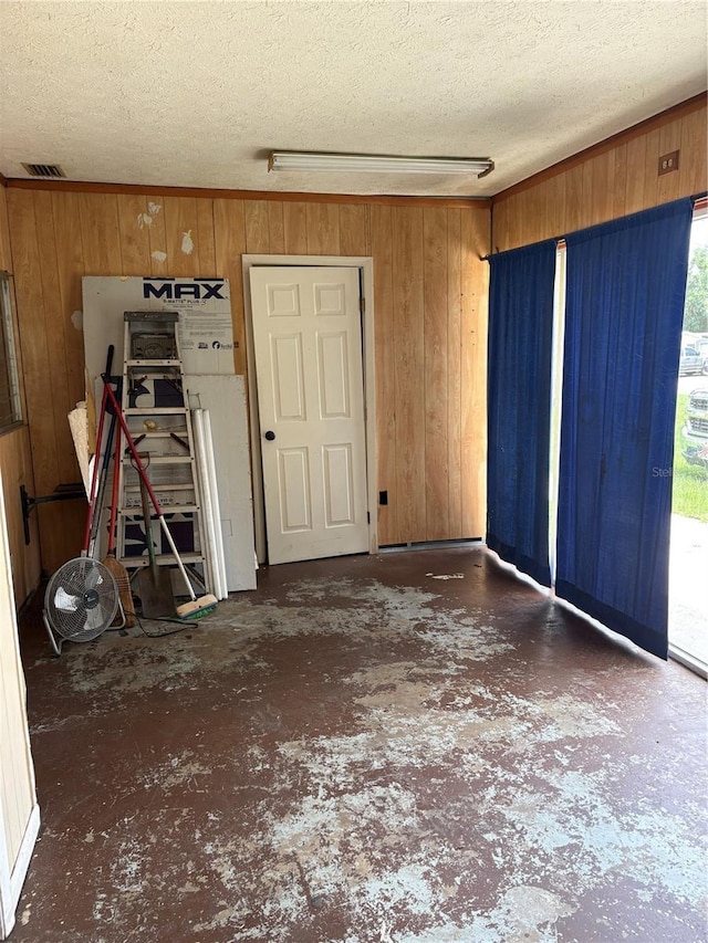 1214 Mitchell St, Brandon, FL 33511 - empty room featuring wood walls, a textured ceiling, unfinished concrete floors, and plenty of natural light