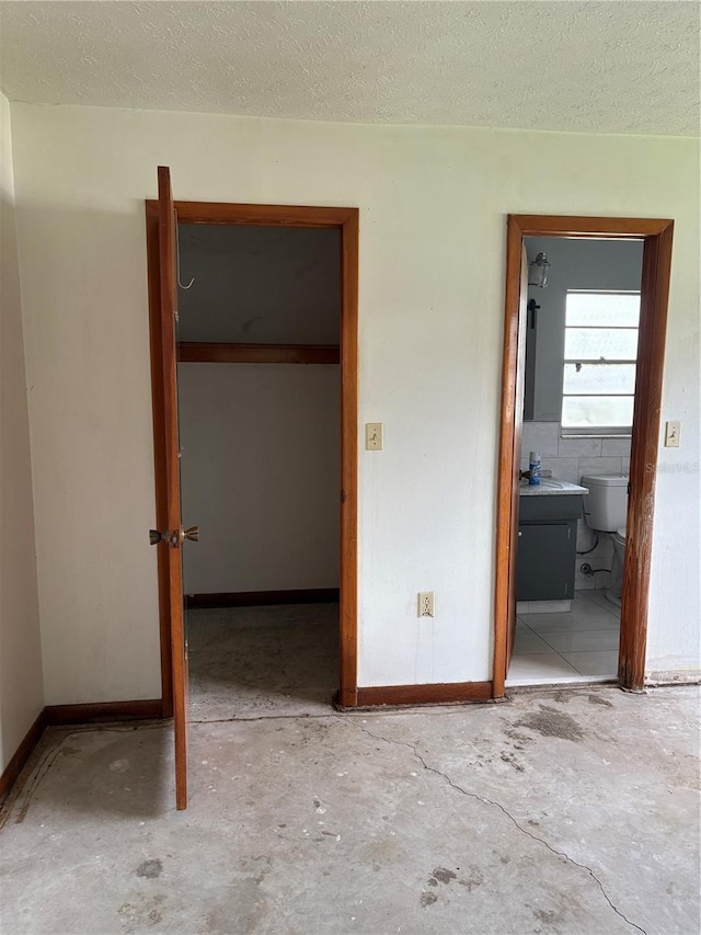 1214 Mitchell St, Brandon, FL 33511 - unfurnished bedroom featuring concrete flooring, a textured ceiling, ensuite bathroom, and a walk in closet