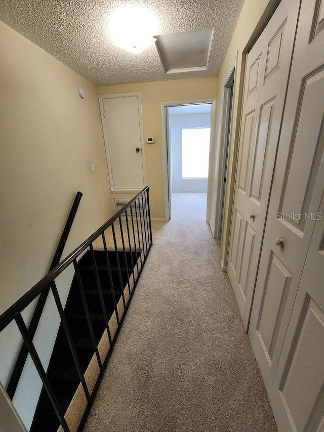 6620 121st Ave Unit 1, Largo, FL 33773 - hall with light colored carpet, a textured ceiling, and an upstairs landing