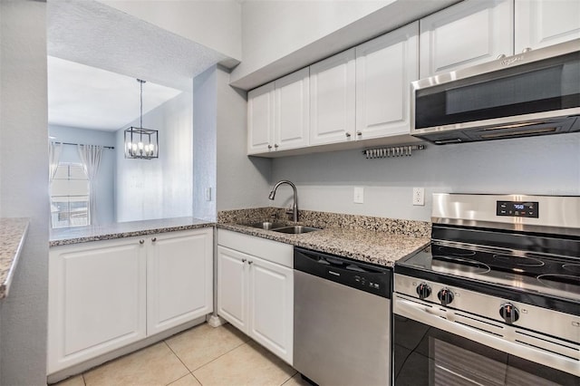 501 S Moody Ave Unit 1134, Tampa, FL 33609 - kitchen featuring stainless steel appliances, white cabinets, light tile patterned floors, a chandelier, and light stone counters