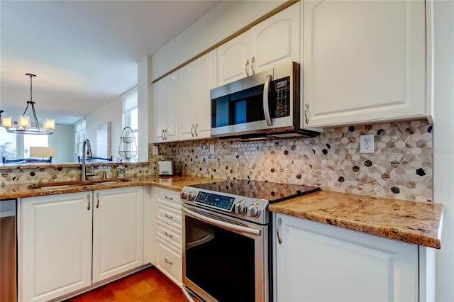 6105 Bahia Del Mar Cir Unit 388, Saint Petersburg, FL 33715 - kitchen featuring appliances with stainless steel finishes, white cabinets, backsplash, and decorative light fixtures