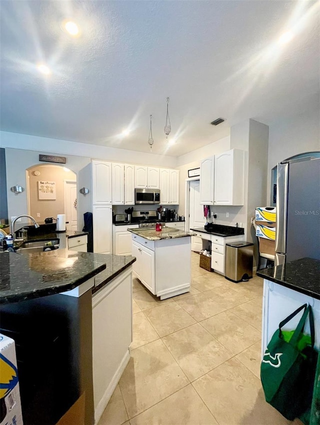 7224 Yardley Way, Tampa, FL 33647 - kitchen featuring stainless steel appliances, arched walkways, a center island, white cabinets, and dark stone countertops