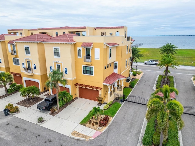 6412 Mayra Shores Ln, Apollo Beach, FL 33572 - view of front of house featuring stucco siding, a garage, concrete driveway, a gate, and a water view
