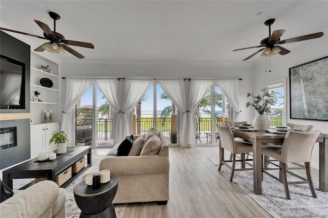 6412 Mayra Shores Ln, Apollo Beach, FL 33572 - living room with ceiling fan, healthy amount of natural light, crown molding, and a glass covered fireplace