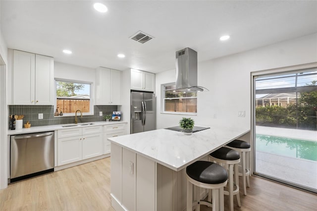 8256 Lark St, Seminole, FL 33777 - kitchen with appliances with stainless steel finishes, island range hood, light wood-style floors, a breakfast bar, and recessed lighting