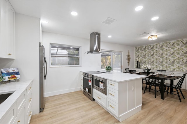 8256 Lark St, Seminole, FL 33777 - kitchen featuring island range hood, wallpapered walls, stainless steel appliances, white cabinetry, and a peninsula