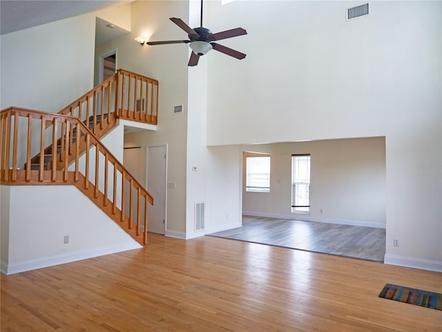 8759 Orient Way NE, Saint Petersburg, FL 33702 - unfurnished living room featuring a high ceiling, wood finished floors, ceiling fan, and stairway
