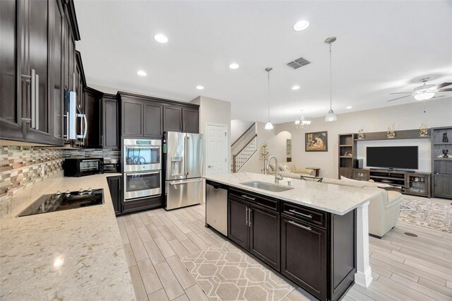 18125 Roseate Dr, Lutz, FL 33558 - kitchen with stainless steel appliances, wood finish floors, light stone counters, backsplash, and an island with sink