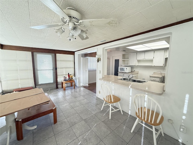 10181 44th Way N Unit 2, Pinellas Park, FL 33782 - kitchen featuring white microwave, ceiling fan, tile patterned flooring, light countertops, and a breakfast bar