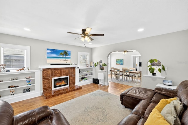 4820 8th Ave S, Saint Petersburg, FL 33711 - living area with arched walkways, ceiling fan, light wood-style flooring, a tiled fireplace, and recessed lighting