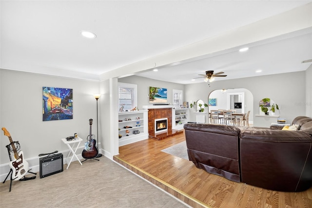4820 8th Ave S, Saint Petersburg, FL 33711 - living room featuring arched walkways, recessed lighting, a ceiling fan, a warm lit fireplace, and wood finished floors