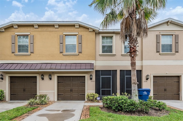 12039 Greengate Dr, Hudson, FL 34669 - townhome / multi-family property with stucco siding, a standing seam roof, an attached garage, driveway, and a metal roof