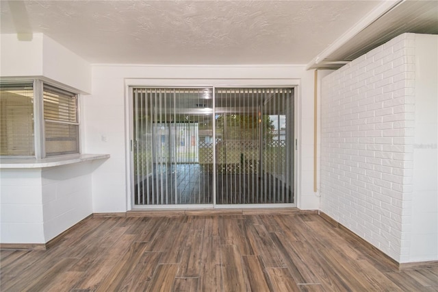 3406 Rock Royal Dr, Holiday, FL 34691 - spare room with wood finished floors, a textured ceiling, and brick wall
