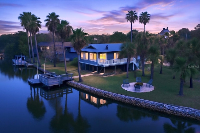 12046 W Gulf Breeze Ct, Crystal River, FL 34429 - back of property at dusk with an outdoor fire pit, a yard, and a deck with water view