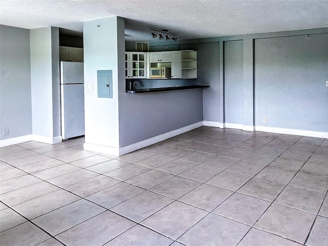 3315 58th Ave S Unit 409, Saint Petersburg, FL 33712 - unfurnished living room featuring a textured ceiling, electric panel, light tile patterned flooring, and track lighting