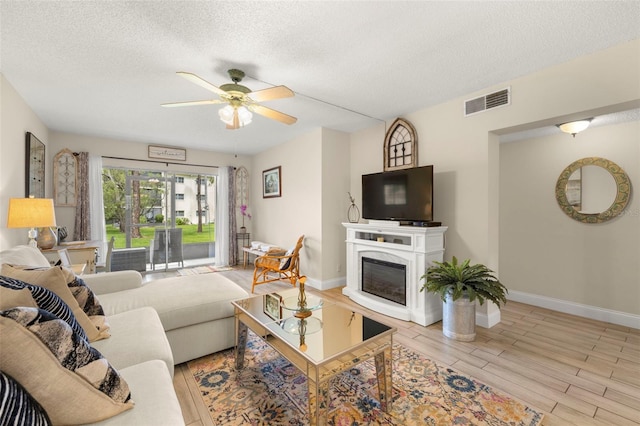 1370 Heather Ridge Blvd Unit 105, Dunedin, FL 34698 - living area featuring ceiling fan, a textured ceiling, wood finished floors, and a glass covered fireplace
