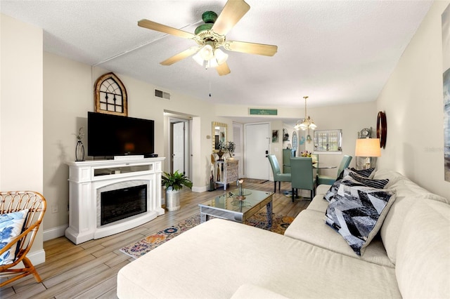 1370 Heather Ridge Blvd Unit 105, Dunedin, FL 34698 - living room featuring wood finished floors, ceiling fan, a chandelier, a textured ceiling, and a premium fireplace