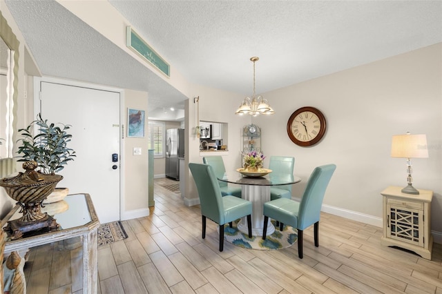 1370 Heather Ridge Blvd Unit 105, Dunedin, FL 34698 - dining room featuring light wood-type flooring, a chandelier, and a textured ceiling