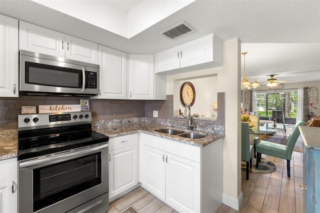 1370 Heather Ridge Blvd Unit 105, Dunedin, FL 34698 - kitchen featuring appliances with stainless steel finishes, light wood finished floors, light stone countertops, white cabinetry, and backsplash