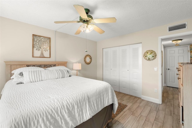 1370 Heather Ridge Blvd Unit 105, Dunedin, FL 34698 - bedroom with light wood finished floors, a closet, ceiling fan, and a textured ceiling