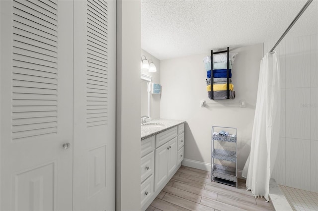 1370 Heather Ridge Blvd Unit 105, Dunedin, FL 34698 - full bathroom featuring vanity, a textured ceiling, tiled shower, a closet, and wood finished floors
