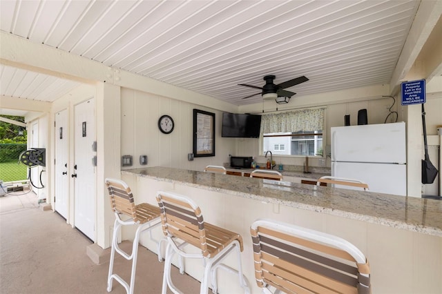 1370 Heather Ridge Blvd Unit 105, Dunedin, FL 34698 - kitchen featuring freestanding refrigerator, wood ceiling, light stone counters, concrete floors, and black microwave