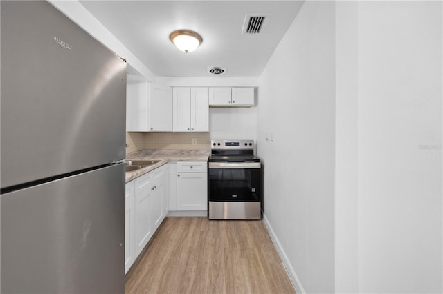 4923 Avery Rd, New Port Richey, FL 34652 - kitchen featuring stainless steel appliances, light wood-style floors, white cabinetry, and tasteful backsplash