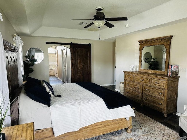 10080 SE 69th Ter, Belleview, FL 34420 - bedroom with a tray ceiling, arched walkways, ensuite bathroom, wood finished floors, and a ceiling fan